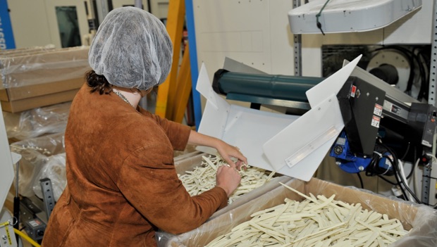 LCI employee wearing a hairnet, assembling the plastic cutlery