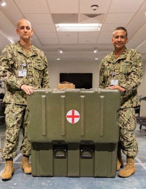 two male military personnel opening a large medical kitting unit